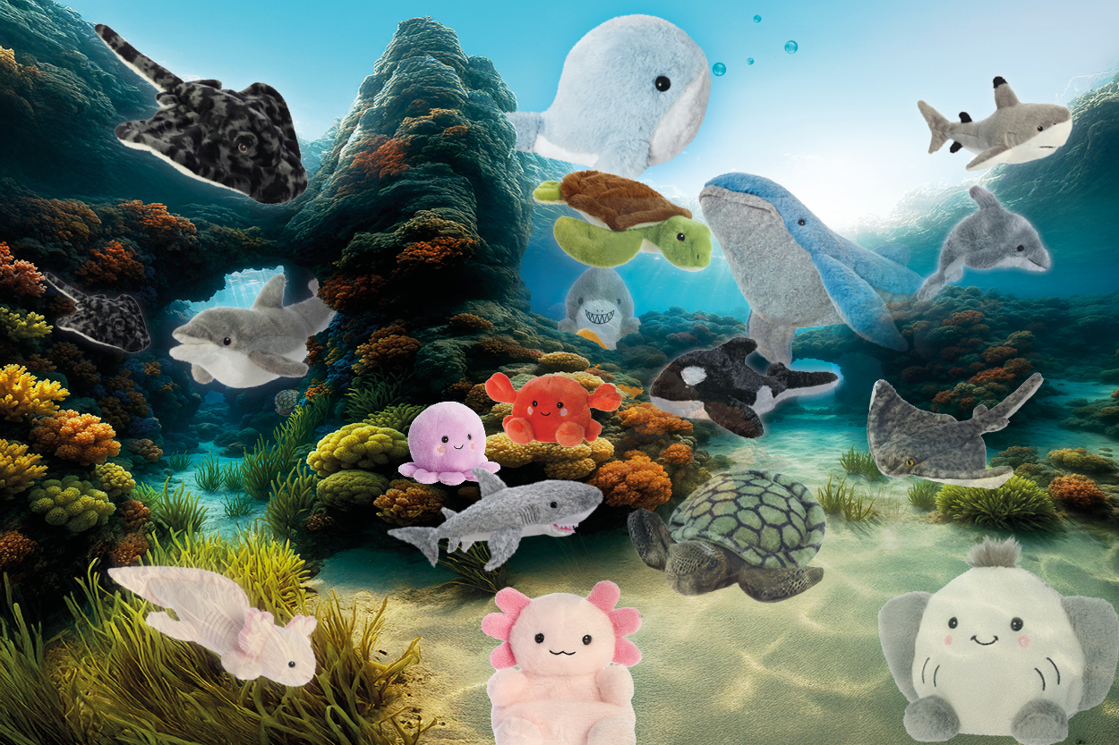 Plüschtiere verschiedener Meeresbewohner, darunter Wale, Haie, Schildkröten und Seesterne, in einer lebhaften Unterwasserlandschaft.