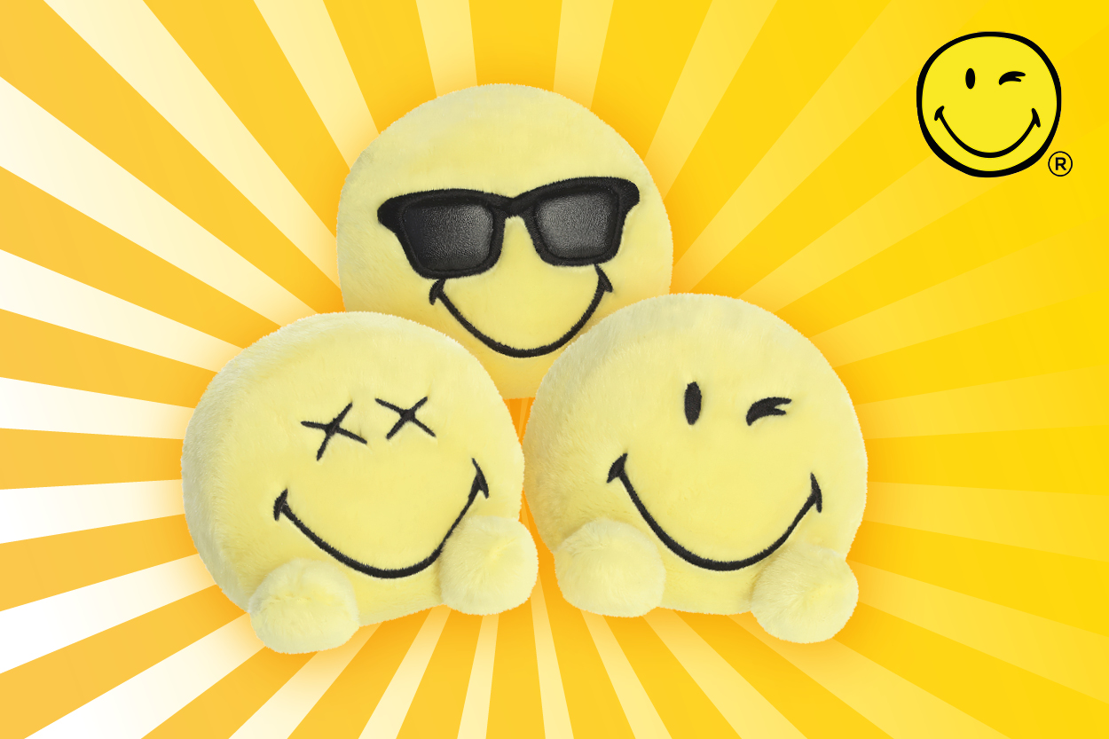 Drei gelbe Smiley-Kissen mit verschiedenen Gesichtsausdrücken: eines mit Sonnenbrille, eines mit X-Augen und eines mit einem breiten Lächeln.