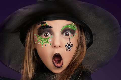Mädchen, das mit Face-Art-Stickern als Hexe verkleidet ist.