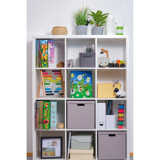 Regal mit verschiedenen Fächern, gefüllt mit Büchern, Spielzeug, Pflanzen und Aufbewahrungsboxen in neutralen Farben.