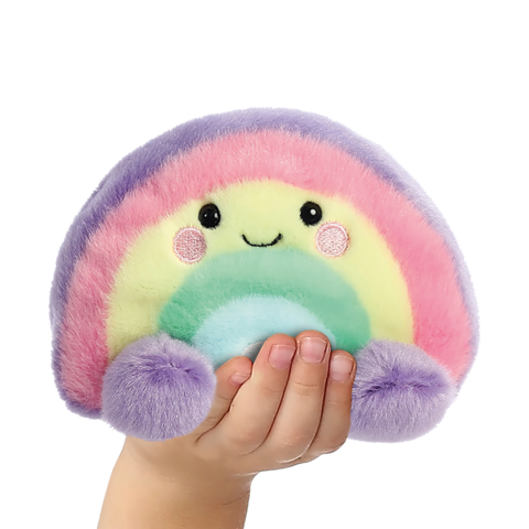 Eine Hand hält ein farbenfrohes, kuscheliges Regenbogen-Plüschtier mit einem lächelnden Gesicht und runden, bunten Details.