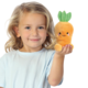 Ein kleines Kind mit blonden Locken hält ein orangefarbenes, plüschiges Karotten-Spielzeug in der Hand und lächelt.