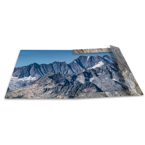 Berglandschaft mit schroffen Gipfeln und Tälern, unter klarem Himmel. Die Szenerie zeigt eine beeindruckende natürliche Umgebung.