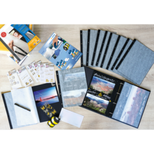 Ein Scrapbook-Set mit leeren Seiten, Aufklebern, einem Stift und verschiedenen Zubehörteilen zum Gestalten von Fotoalben.