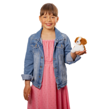 Ein Mädchen in einem rosa Kleid und einer Jeansjacke hält ein Hundestofftier in der Hand und lächelt.