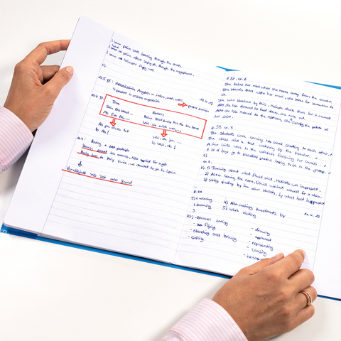 Eine Person hält ein offenes Notizbuch mit handschriftlichen Notizen und Markierungen. Einige Absätze sind markant hervorgehoben.