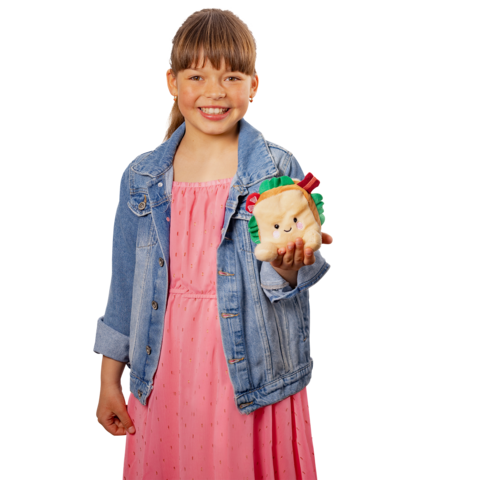 Ein Mädchen in einem rosa Kleid und einer Jeansjacke hält ein plüschiges Tier-Spielzeug, das einen Hamburger in den Pfoten hält.