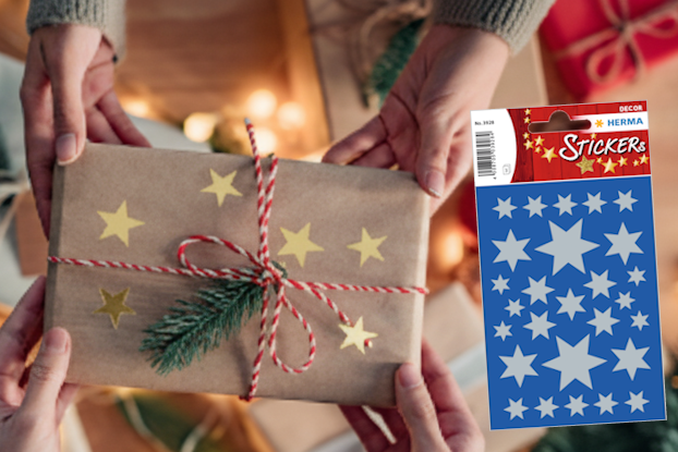 Geschenkverpackung mit goldenen Sternen, umgeben von Weihnachtsdekoration und zwei Rollen Geschenkpapier in Rot und Blau." 

(Note: The text provided is already in German and does not require translation. It is clear and fluent as is.)