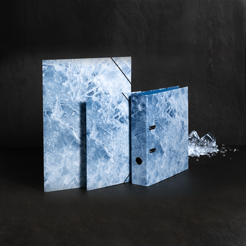 Drei Ordner mit einem blauen, marmorierten Design stehen auf einer dunklen Oberfläche, umgeben von Eisstücken.