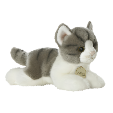 Plüschkatze in Grau und Weiß, liegend mit aufmerksamen Augen und einem kleinen Anhänger.