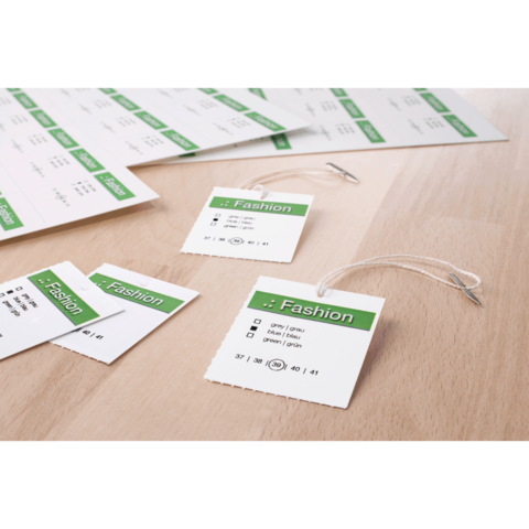 Mehrere Etiketten mit dem Wort "Fashion" und Größenangaben auf einem Holzuntergrund. Einige Etiketten sind mit Schnüren versehen.