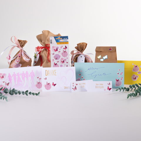 Geschenktüten und Karten in verschiedenen Farben und Designs, darunter eine 'Danke'-Karte und eine 'Alles Gute'-Karte, verziert mit Schmetterlingen.