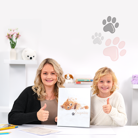 Eine Frau und ein Kind halten ein Katzenbuch und zeigen Daumen hoch. Im Hintergrund sind Pfotenabdrücke und verschiedene Dekorationen zu sehen.