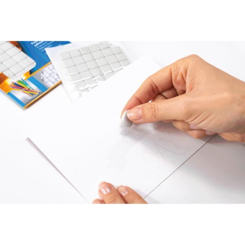 Eine Hand verwendet einen Radiergummi, um eine Bleistiftzeichnung auf einem Blatt Papier zu löschen, während im Hintergrund ein Set von Aufklebern sichtbar ist.