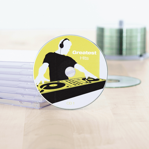 CD mit dem Titel 'Greatest Hits' und einem DJ-Design, umgeben von durchsichtigen CD-Hüllen auf einem Tisch.