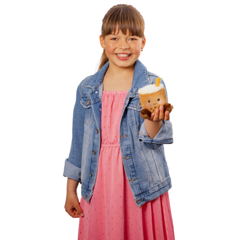 Ein Mädchen in einem rosa Kleid und einer Jeansjacke hält ein süßes, plüschiges Getränk in der Hand und lächelt freundlich.