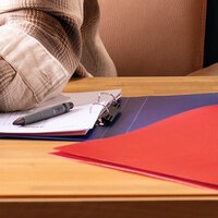 Blaues und rotes Ringbuch auf Schreibtisch
