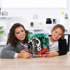 Zwei Mädchen halten ein Fußballzeugnis mit einer Grafik und der Punktzahl 3:2. Sie sitzen an einem Tisch in einem hellen Raum.
