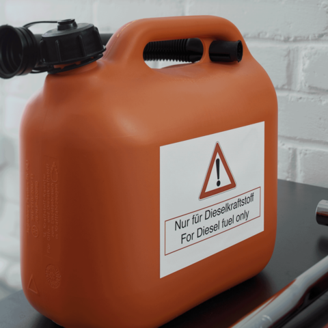 Ein orangefarbener Kanister mit einem Warnschild, das besagt: "Nur für Dieselkraftstoff" in deutscher und englischer Sprache.