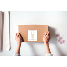 Eine Person hält ein braunes Paket mit einem Etikett, das "Frohe Weihnachten und ein glückliches neues Jahr" zeigt.