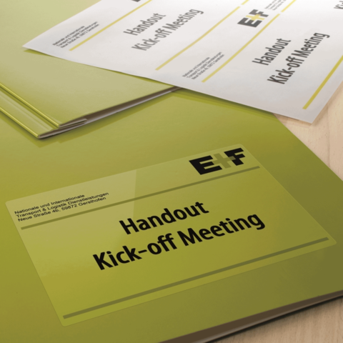 Handouts für ein Kick-off-Meeting in grünen Ordnern, mit dem Titel "Handout Kick-off Meeting" deutlich sichtbar.