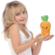 Ein Mädchen mit blonden Haaren hält ein orangefarbenes, karottenförmiges Plüschtier mit einem lächelnden Gesicht in den Händen.