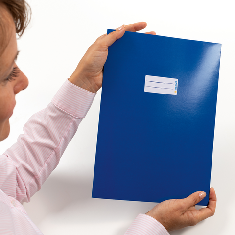 Eine Person hält eine blaue Mappe mit einem Aufkleber auf der Vorderseite in der Hand." 

(Note: The text is already in German and does not require translation. It is clear and fluent as is.)