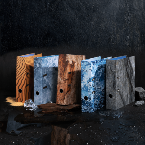 Farbenfrohe Ordner in verschiedenen Texturen stehen nebeneinander, darunter Holz-, Stein- und Wasseroptik, auf einer dunklen Oberfläche.