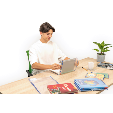 Ein junger Mann sitzt an einem Tisch, nutzt ein Tablet und hat Schulbücher sowie Schreibmaterialien vor sich. Eine Pflanze steht daneben.