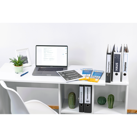 Schreibtisch mit Laptop, Dokumenten, Ordnern und Pflanzen. Ordner sind beschriftet mit "Haus" und "Business".