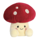 Kuscheliges Pilzplüschtier mit rotem Hut und weißen Punkten, lächelnd und mit runden, freundlichen Augen.