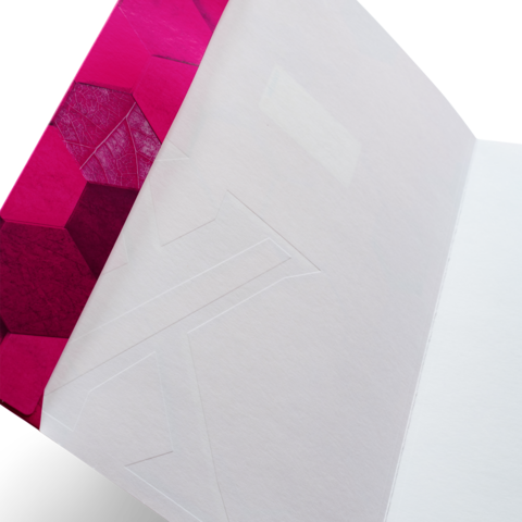 Ein offenes Notizbuch mit einer pinken, geometrisch gemusterten Einbandseite und einer leeren, weißen Innenseite.