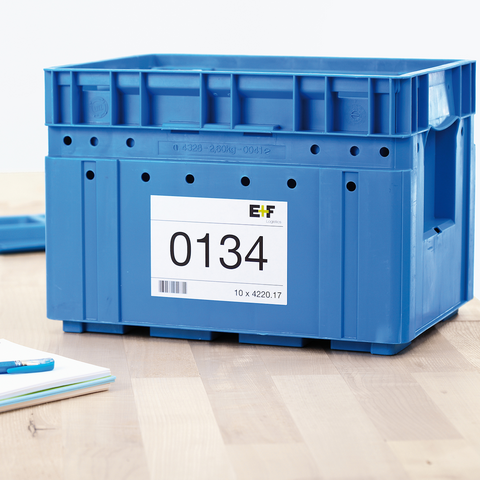 Blaue Kunststoffbox mit einer Etikette, die die Nummer 0134 zeigt, auf einem Tisch neben einem Notizblock und einem Stift.