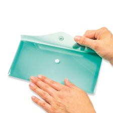 Eine Hand hält einen flachen, mintgrünen Behälter mit einem Deckel, während die andere Hand den Behälter berührt.