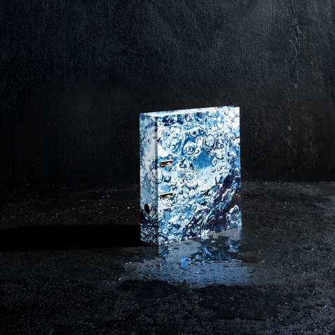 Ein Ordner mit einem Wasserdesign steht auf einer nassen Oberfläche, umgeben von Wassertröpfchen und reflektierenden Oberflächen.