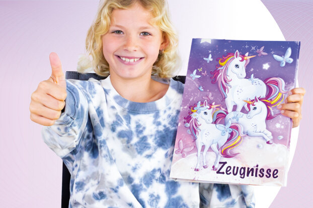 Ein Mädchen lächelt und zeigt mit dem Daumen nach oben, während es einen bunten Ordner mit einem Einhorn-Design und leeren Seiten in der Hand hält.