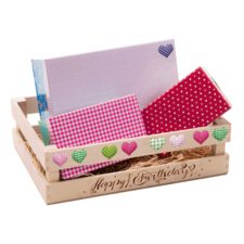 Holzkiste mit bunten Geschenkverpackungen in verschiedenen Mustern, beschriftet mit "Happy Birthday".